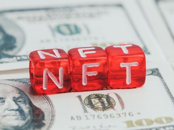 non fungible tokenabbreviated as NFT in white letters on red dice against the background of dollars (Getty Images)