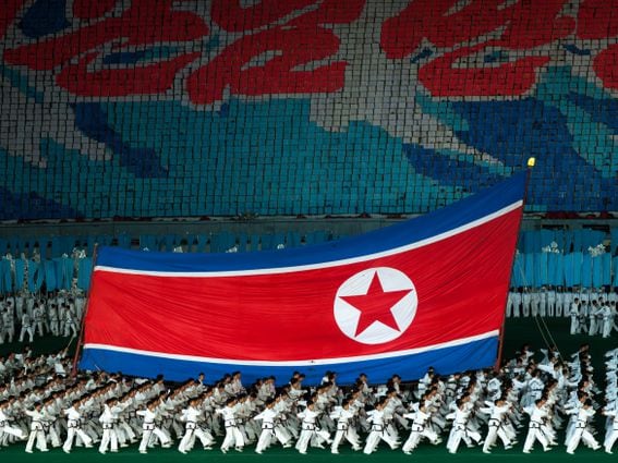 PYONGYANG, NORTH KOREA - SEPTEMBER 09: North Korean taekwondo team in front of a giant flag during the Arirang mass games in may day stadium, Pyongan Province, Pyongyang, North Korea on September 9, 2011 in Pyongyang, North Korea.