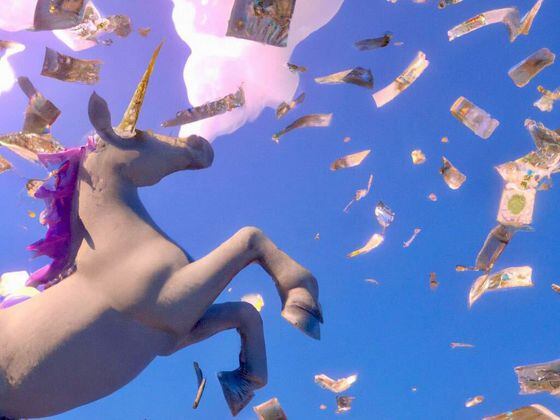 Unicorn flying through paper currency (Dall-E/CoinDesk)