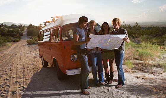 Friends on a road trip looking at a map lost (Image Source/Getty Images)