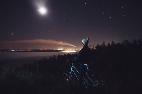 woman-with-a-bicycle-looking-at-the-night-landscape