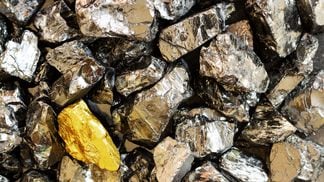 golden-bar-on-background-of-raw-coal-nuggets-close-up