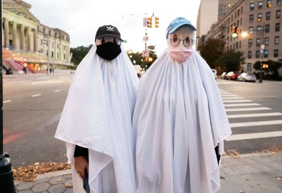People dressed as ghosts wear face masks outside the Brooklyn Museum on October 31, 2020 in New York City.
