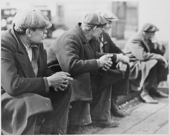 Row_of_men_at_the_New_York_City_docks_out_of_work_during_the_depression,_1934_-_NARA_-_518288