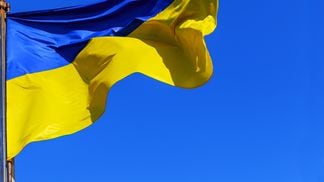 The national yellow and blue flag of Ukraine over the sky and clouds. (Valentyn Semenov / Getty)