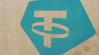 Tether 's logo painted on a wooden background.