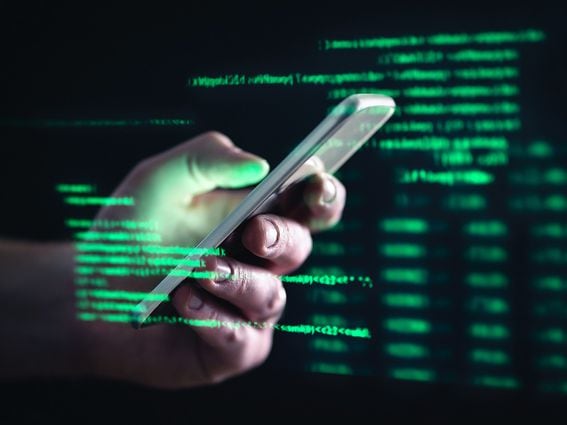 CDCROP: Darkweb, darknet and hacking concept. Hacker with cellphone. Man using dark web with smartphone. Mobile phone fraud, online scam and cyber security threat. Scammer using stolen cell. (Getty Images)