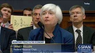 Christian Langlais holds up a "Buy Bitcoin" sign behind Federal Reserve Chair Janet Yellen at a House Financial Services Committee hearing in July 2017. (C-Span)