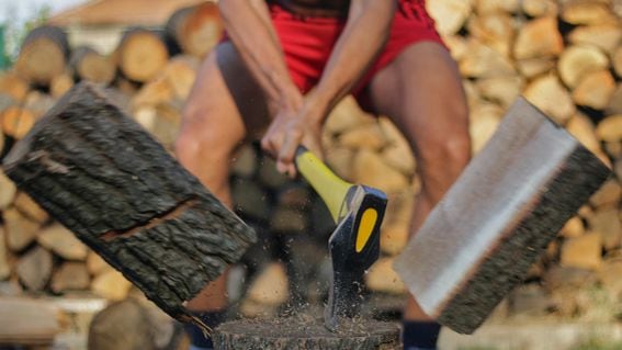 image of someone splitting a log vertically in half with a long-handled ax