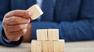 CDCROP: Shot of an unrecognisable businessman working with wooden building blocks in a modern office (iStockphoto/Getty Images)