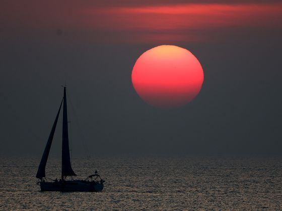 CDCROP: A sail boat passing the sunset is seen during the Emirates Intercontinental Beach Soccer Cup 2022 (Francois Nel/Getty Images)
