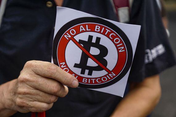SAN SALVADOR, EL SALVADOR - AUGUST 27: A veteran holds a sticker against Bitcoin during a protest against the bitcoin law by veterans of the Salvadoran civil war on August 27, 2021 in San Salvador, El Salvador. The new bitcoin law should come into force on September 7. (Photo by Roque Alvarenga/APHOTOGRAFIA/Getty Images)