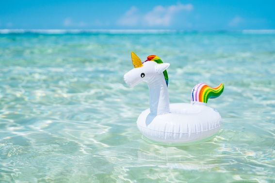 inflatable-white-unicorn-floating-at-transparent-turquoise-sea-blue-sky-with-few-clouds-on-the-background