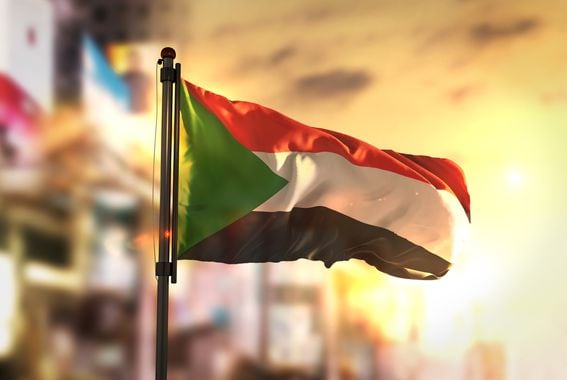 Sudan Flag Against City Blurred Background At Sunrise Backlight (NatanaelGinting/ Getty)