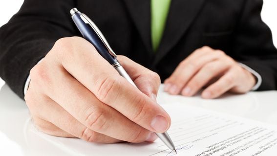 hand holding a pen to sign a document
