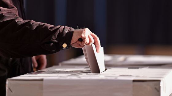 Hand of a person casting a vote into the ballot box during elections