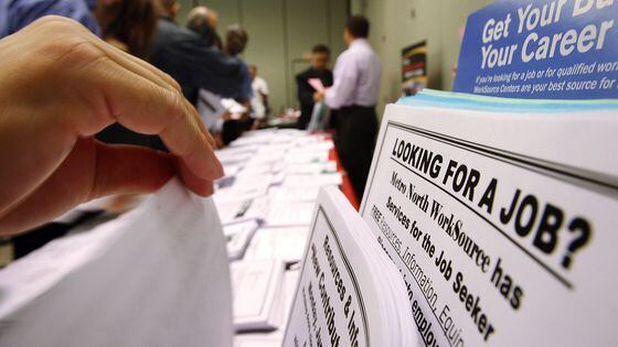 Job seekers look over job opening fliers at the WorkSource exhibit. (David McNew/Getty Images)