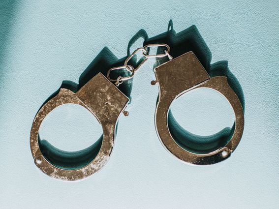 Simple Conceptual Image of Silver Handcuffs on Blue Surface