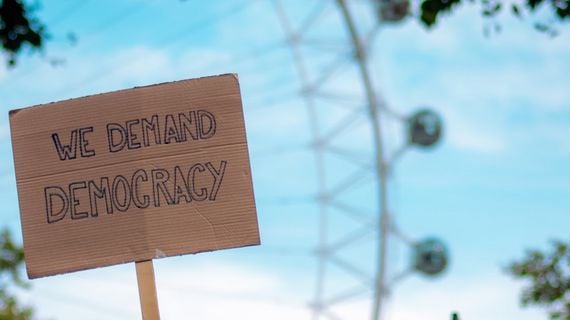 we demand democracy protest sign (Fred Moon/Unsplash, modified by CoinDesk)