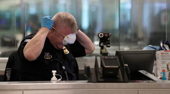 WELCOME TO 2020: A U.S. Customs and Border Protection (CBP) officer dons the N95 respirator prior to the arrival of international passengers at Dulles International Airport, March 13. (Credit: CBP/Wikimedia Commons)