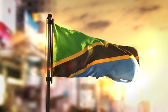 Tanzania Flag Against City Blurred Background At Sunrise Backlight (Getty Images/stockphoto)
