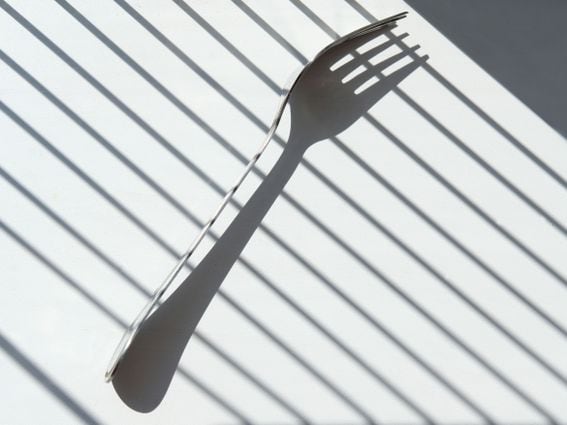 Metal fork with an interesting dark shadow on a white background, representing Ethereum's shadow fork 9