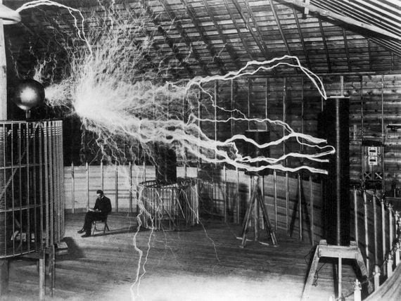 Inventor and scientist Nikola Tesla in his lab while his magnifying transmitter high voltage generator produces bolts of electricity. December 1899. (Getty Images)