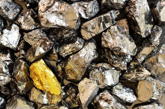 Golden bar on background of raw coal nuggets close-up