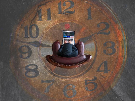 A photo from above of a person working on a computer sitting in the middle of a clock.