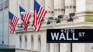Wall Street sign with American flags and New York Stock Exchange in Manhattan, New York City, USA. (Getty Images)