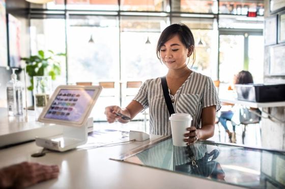 Young woman using credit card reader at coffee shop counter