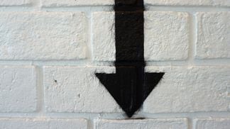 CDCROP: Down Arrow spray painted on a brick wall (Shutterstock)