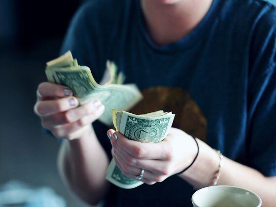 Mujer contando dólares en efectivo. (Alexander Grey/Unsplash)