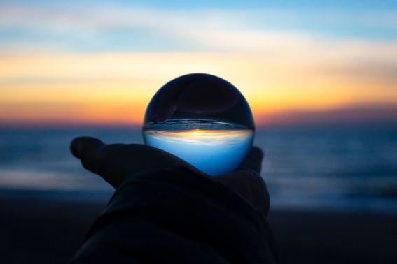 a crystal globe being held up to the horizon, representing Hal Finney predicting bitcoin as a reserve currency, but backing a stablecoin (LUNA, LFG, UST)