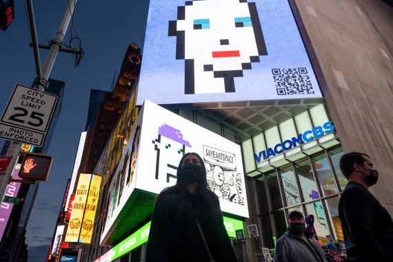 NEW YORK, NEW YORK - MAY 12: People walk past CryptoPunk digital art non-fungible token (NFT) displayed on a digital billboard in Times Square on May 12, 2021 in New York City. The image is part of SaveArtSpace's "Pixelated" public art exhibition which will be displaying 193 of Larva Labs' CryptoPunks on phone booths, bus shelters, and billboards around New York City during the month of May. New York Governor Andrew Cuomo announced pandemic restrictions to be lifted on May 19.  (Photo by Alexi Rosenfeld/Getty Images)