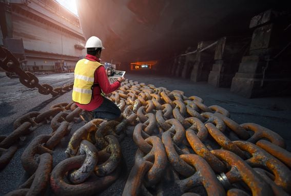 Chain links spread laid out next to a ship's hull in drydock