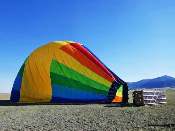 CDCROP: Deflated rainbow colored hot air balloon laying on side (Getty Images)