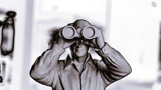 Altered black and white photo of a man holding binoculars.