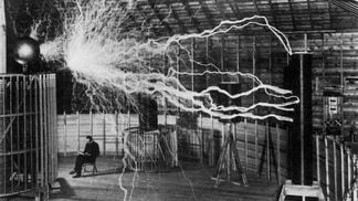 Inventor and scientist Nikola Tesla in his lab while his magnifying transmitter high voltage generator produces bolts of electricity. December 1899. (Getty Images)
