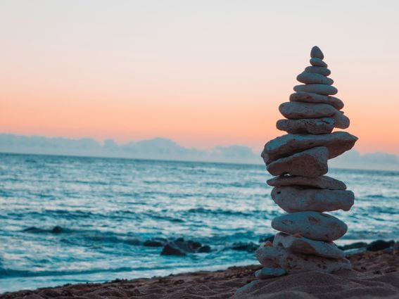 Stablecoins and DeFi growth, represented by stacked rocks on a beach at sunset.