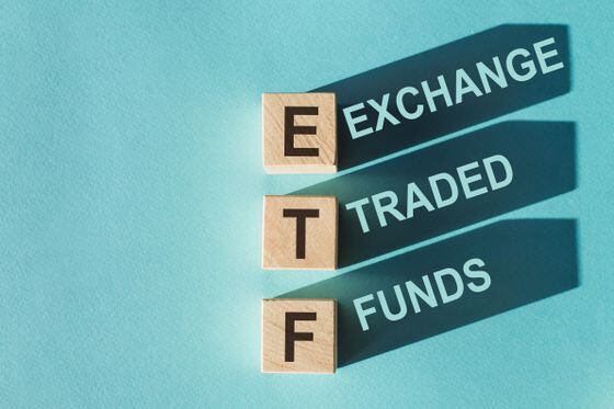 Wooden cubes building word ETF (abbreviation of Exchange Traded Fund) on light blue background
