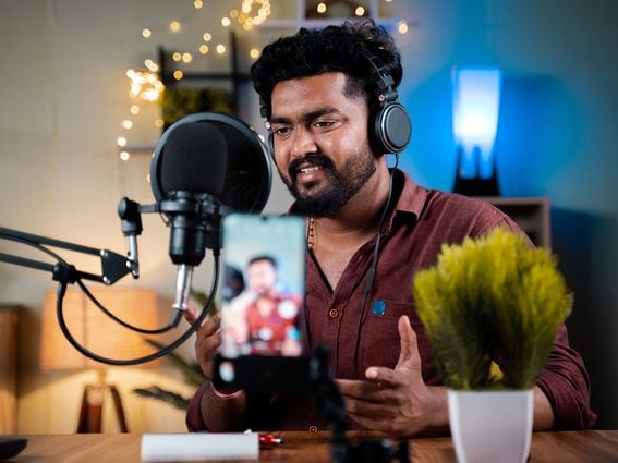 A young Indian social media influencer recording his podcast on a mobile phone. (lakshmiprasad S/Getty Images)