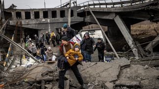 Residents of Irpin flee heavy fighting via a destroyed bridge as Russian forces entered the city on March 7, 2022. (Chris McGrath/Getty Images)