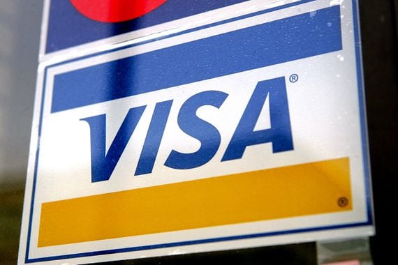 A Visa credit card sign is displayed in a store window in De