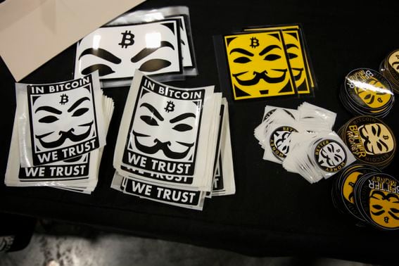 MIAMI, FLORIDA - APRIL 8: Stickers depicting Guy Fawkes masks (Anonymous mask) and the bitcoin logo are seen at a stand in the exhibition hall during the Bitcoin 2022 Conference at Miami Beach Convention Center on April 8, 2022 in Miami, Florida. The worlds largest bitcoin conference runs from April 6-9, expecting over 30,000 people in attendance and over 7 million live stream viewers worldwide.(Photo by Marco Bello/Getty Images)