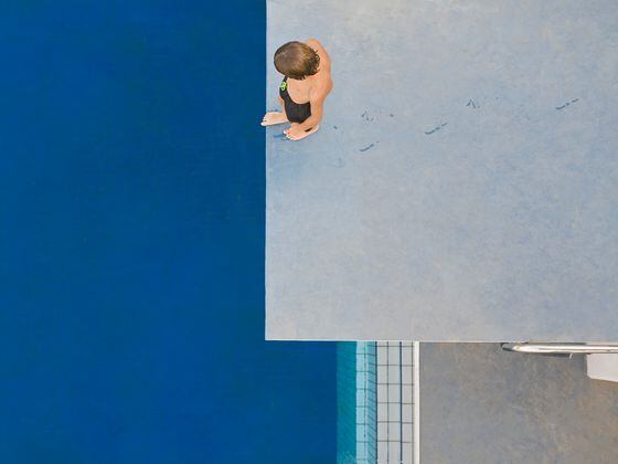 Boy (6-7) standing on diving board, overhead view