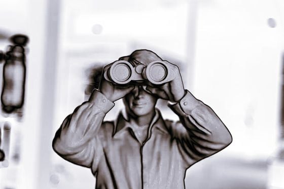 Altered black and white photo of a man holding binoculars.