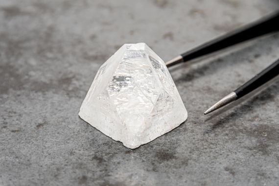 raw-diamond-big-dob-on-concrete-surface-next-to-tweezers