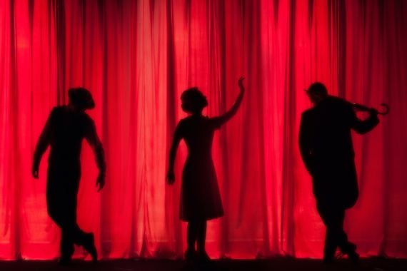silhouette of three performers on stage.