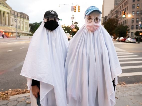 People dressed as ghosts wear face masks outside the Brooklyn Museum on October 31, 2020 in New York City.